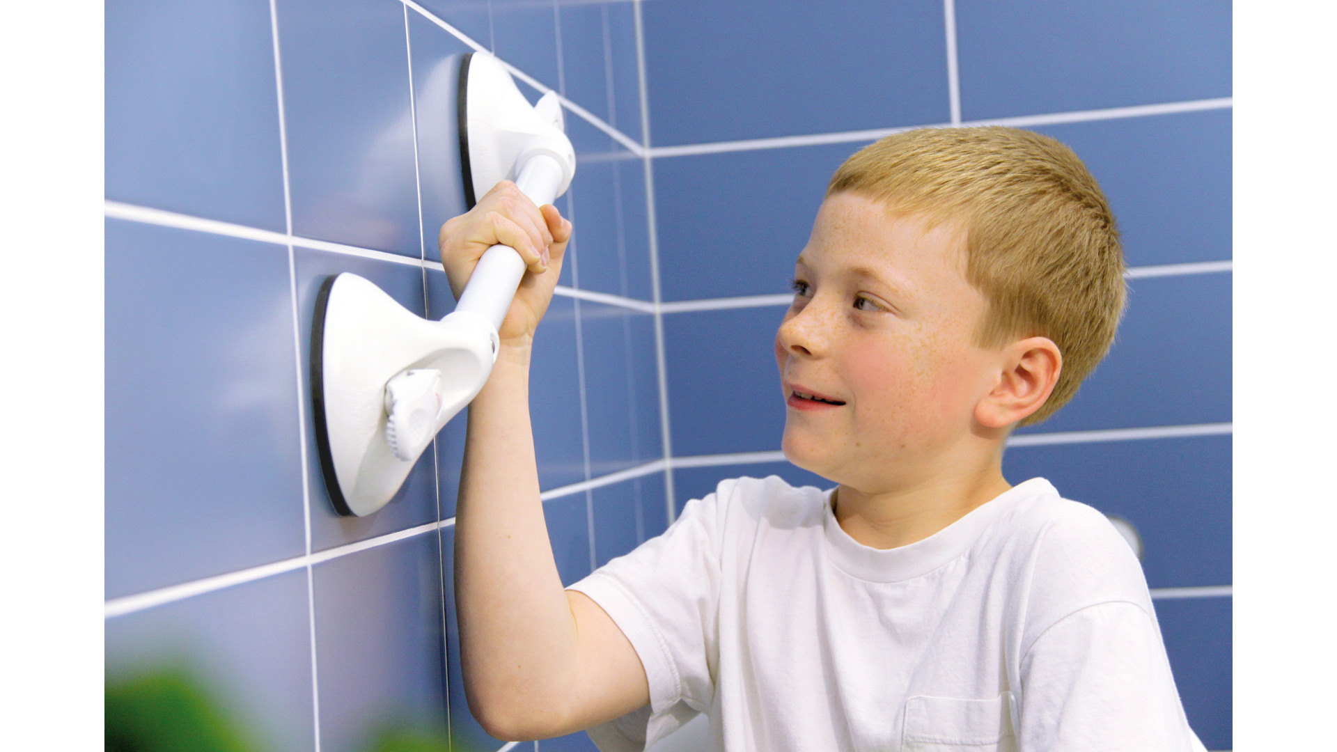 Ein Kind hält sich fest an einem mmit Saugnäpfen an den Wandfliesen befestigtem Haltegriff