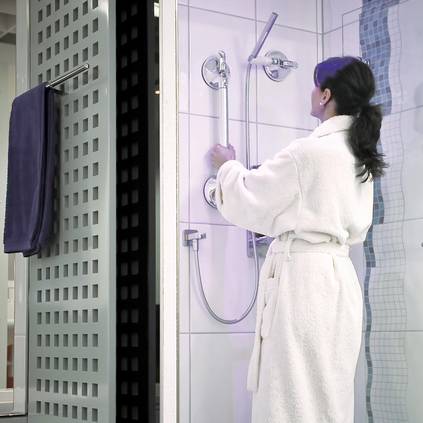 Eine Frau hält sich in einer Dusche an einem vertikalen Haltegriff fest.